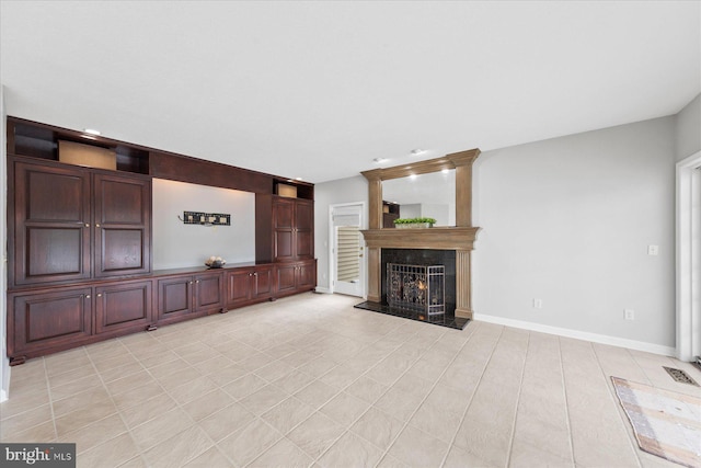 unfurnished living room featuring baseboards, a lit fireplace, and visible vents