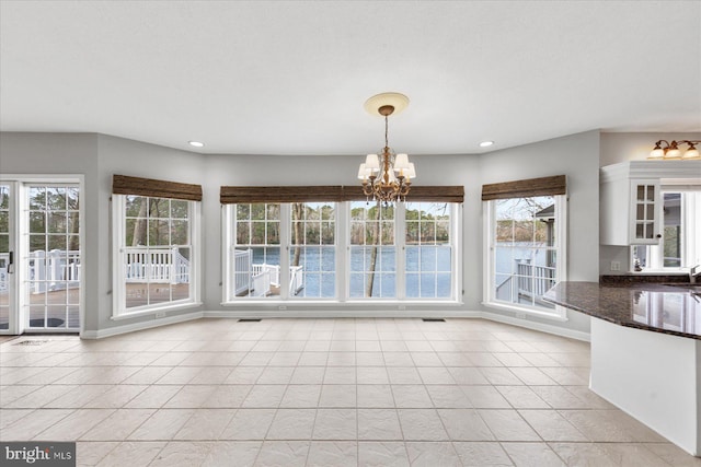 unfurnished dining area with a sink, light tile patterned floors, recessed lighting, and a chandelier