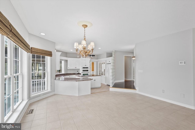 kitchen featuring white cabinetry, a chandelier, hanging light fixtures, visible vents, and a peninsula