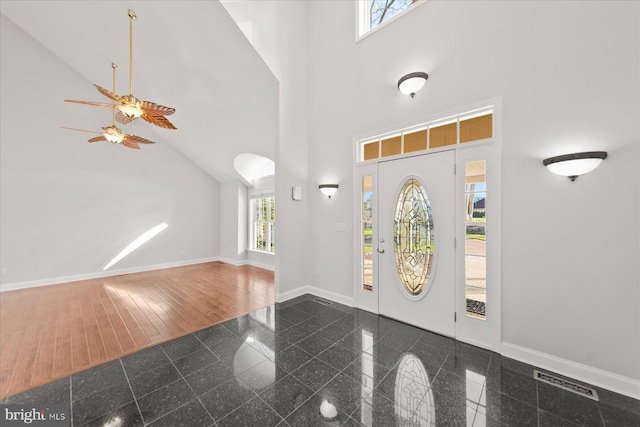 foyer featuring a towering ceiling, baseboards, granite finish floor, and visible vents