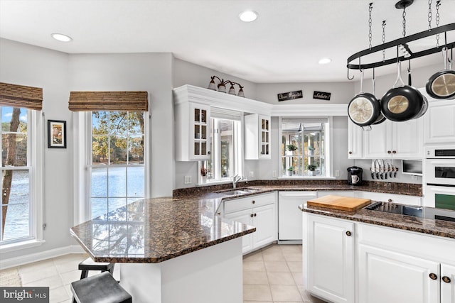 kitchen featuring white appliances, white cabinetry, glass insert cabinets, and a sink