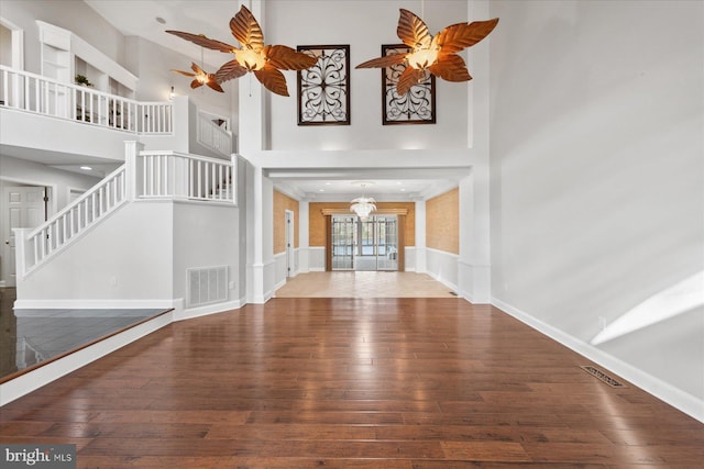 interior space featuring stairs, visible vents, ceiling fan with notable chandelier, and wood-type flooring