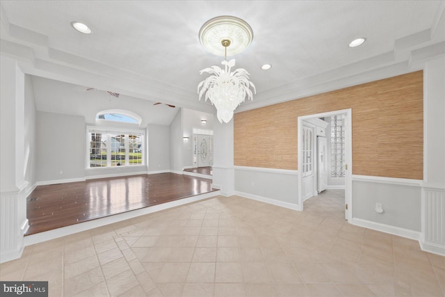 tiled empty room with a wainscoted wall, a notable chandelier, vaulted ceiling, baseboards, and recessed lighting