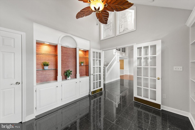 foyer entrance with baseboards, stairs, a towering ceiling, a ceiling fan, and granite finish floor