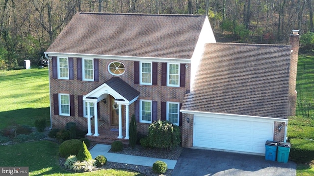 colonial house featuring a garage and a front lawn