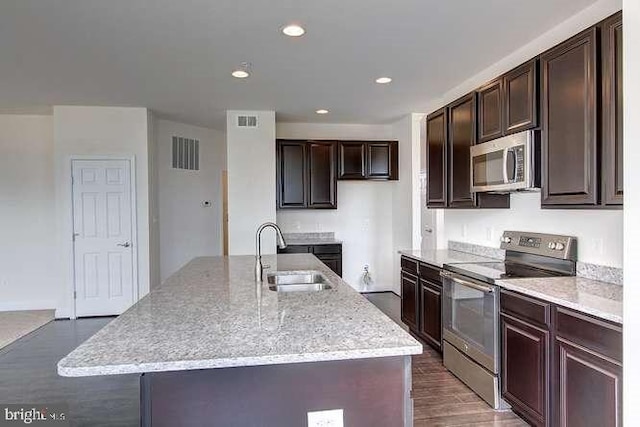 kitchen with sink, stainless steel appliances, dark hardwood / wood-style flooring, and a center island with sink