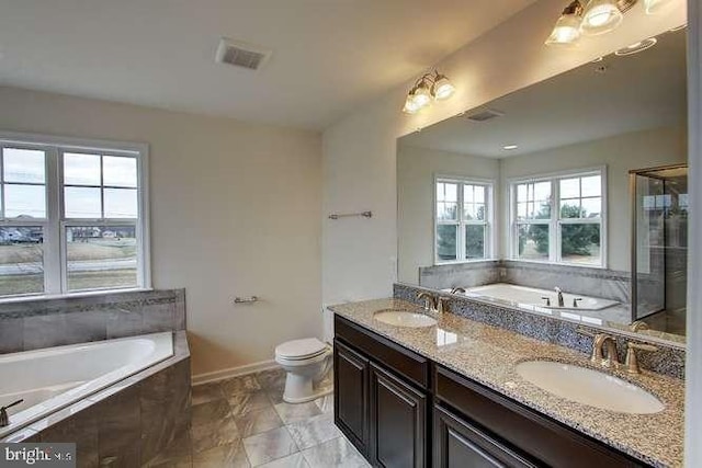 bathroom featuring a healthy amount of sunlight, vanity, a relaxing tiled tub, and toilet