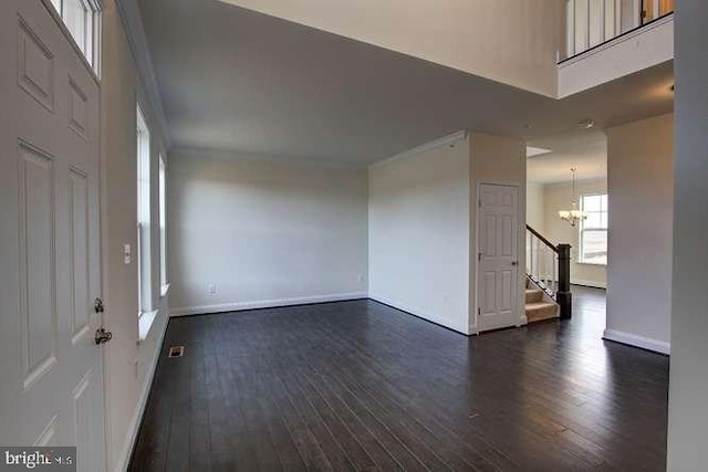 spare room with ornamental molding, dark wood-type flooring, and a chandelier