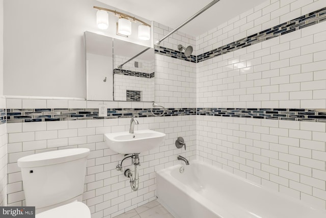 full bathroom featuring sink, tiled shower / bath, tile walls, and toilet