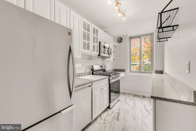 kitchen with sink, stainless steel appliances, white cabinetry, and dark stone countertops