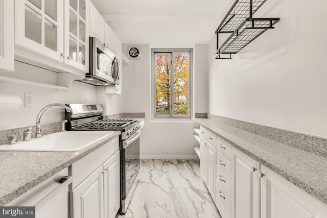 kitchen featuring white cabinets, light stone counters, sink, and appliances with stainless steel finishes