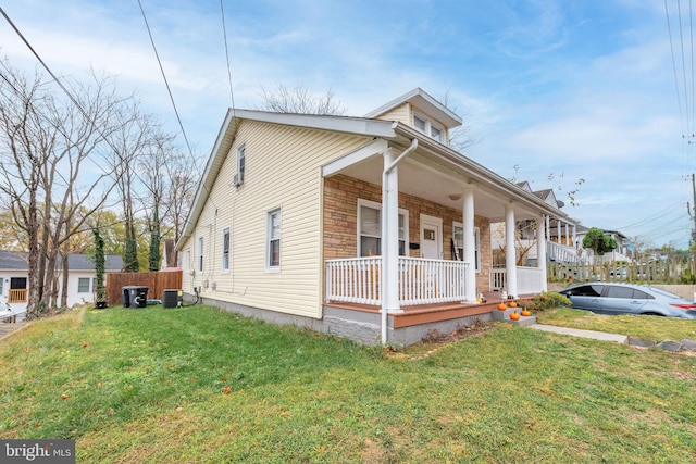 view of front of property featuring covered porch, central AC unit, and a front yard