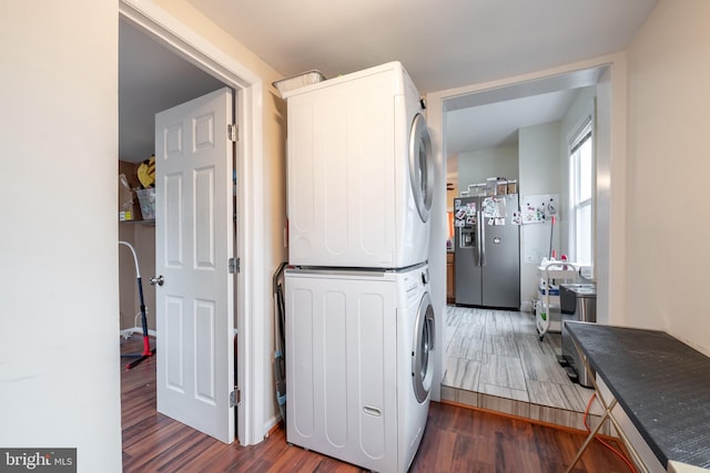 laundry area featuring dark wood-type flooring and stacked washer / drying machine