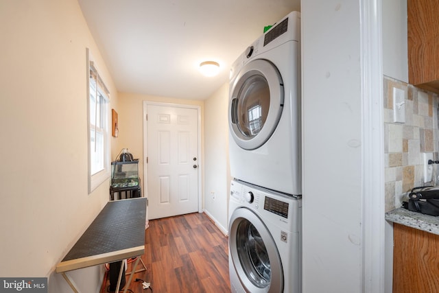 laundry room with dark wood-type flooring and stacked washer / drying machine