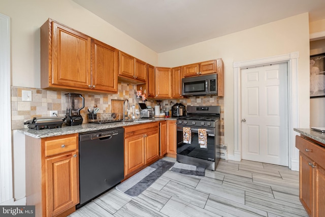 kitchen with stainless steel appliances, light stone counters, tasteful backsplash, and sink