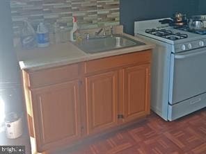 kitchen featuring backsplash, white range with gas cooktop, and sink