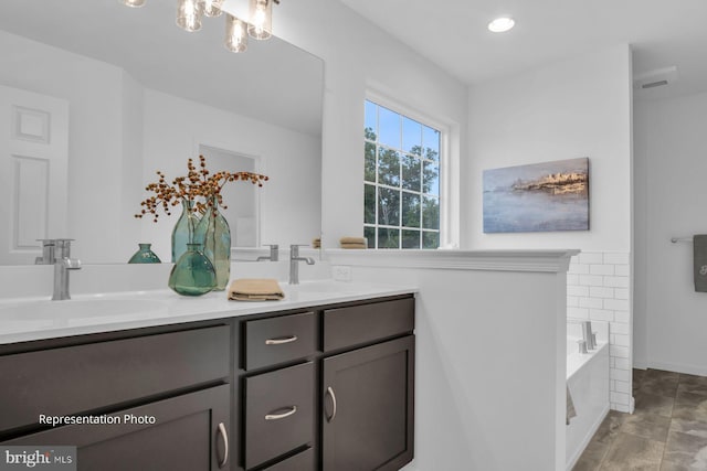 bathroom featuring vanity and tiled bath