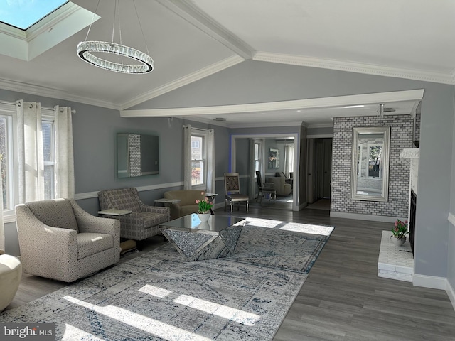 living room with an inviting chandelier, lofted ceiling with skylight, dark wood-type flooring, and ornamental molding