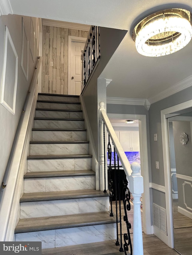 staircase with hardwood / wood-style floors and ornamental molding