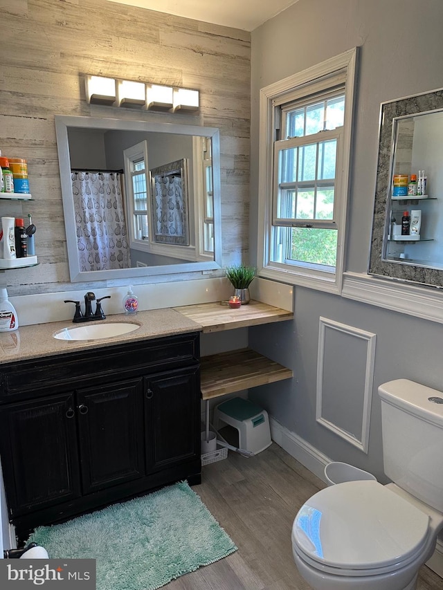 bathroom featuring curtained shower, toilet, wooden walls, vanity, and hardwood / wood-style flooring