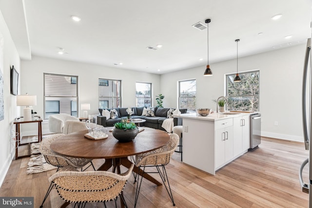 dining area featuring sink, light hardwood / wood-style flooring, and a healthy amount of sunlight