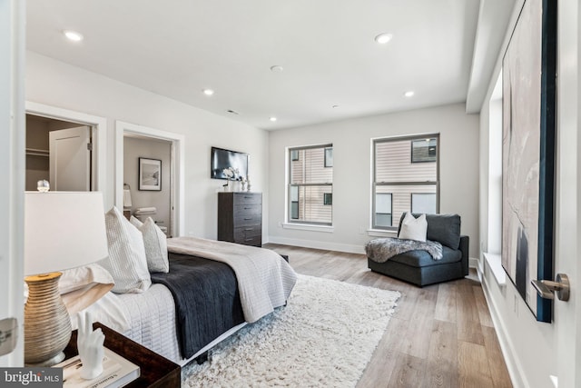 bedroom with ensuite bathroom and light wood-type flooring