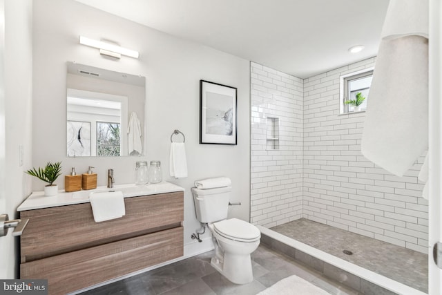 bathroom with vanity, toilet, and a tile shower