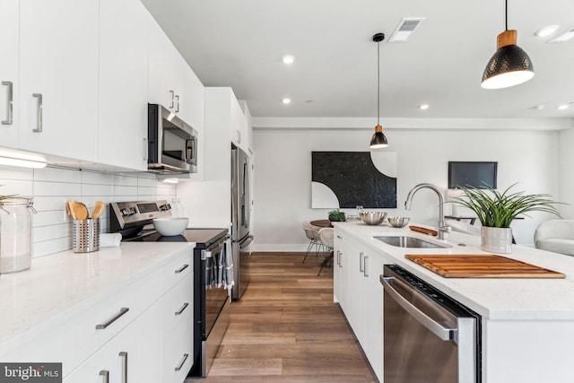 kitchen featuring white cabinetry, stainless steel appliances, sink, and hanging light fixtures