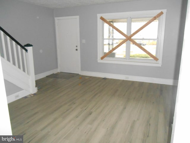 unfurnished living room featuring a healthy amount of sunlight, wood-type flooring, and a textured ceiling