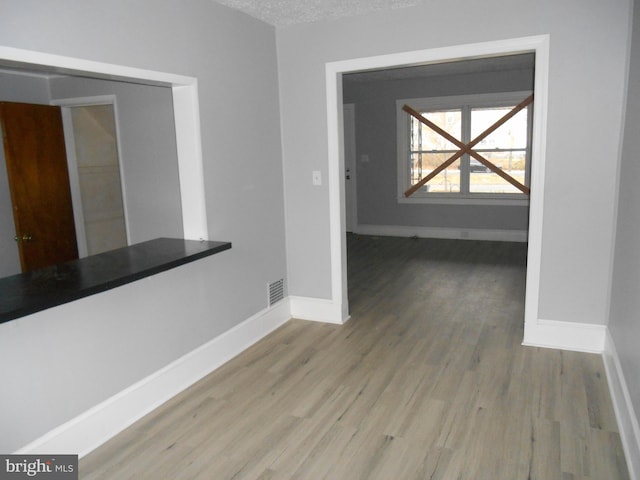 hallway with light hardwood / wood-style floors and a textured ceiling