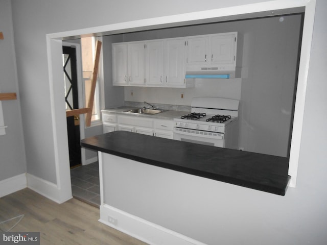 kitchen featuring white cabinets, light hardwood / wood-style floors, white range with gas cooktop, and sink