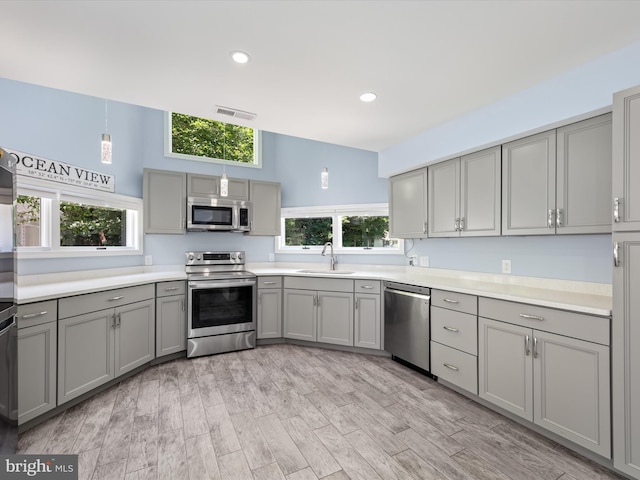 kitchen featuring appliances with stainless steel finishes, light wood-type flooring, plenty of natural light, and sink