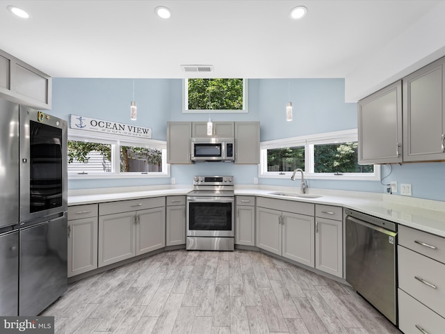 kitchen with appliances with stainless steel finishes, light wood-type flooring, plenty of natural light, and sink