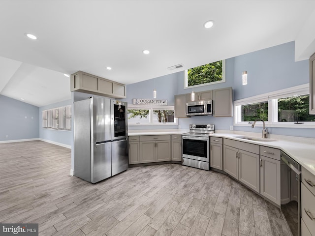 kitchen featuring pendant lighting, stainless steel appliances, light hardwood / wood-style floors, and sink