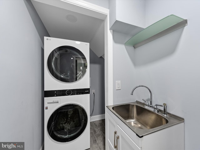 washroom featuring hardwood / wood-style flooring, sink, and stacked washer / dryer