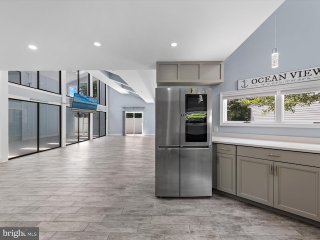 kitchen with gray cabinetry, high vaulted ceiling, decorative light fixtures, light hardwood / wood-style floors, and stainless steel refrigerator