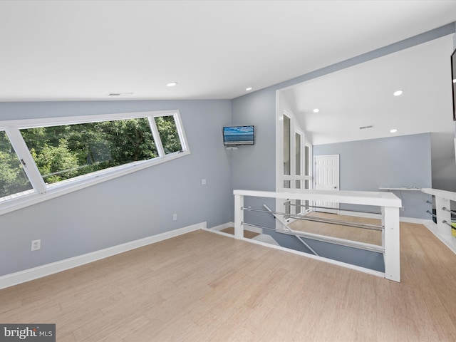 empty room featuring light wood-type flooring and vaulted ceiling