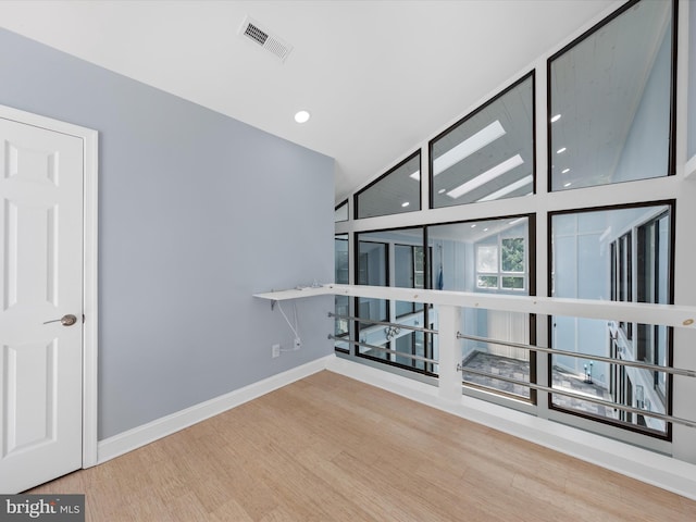 unfurnished room featuring hardwood / wood-style floors and vaulted ceiling