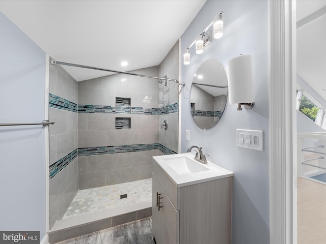 bathroom with hardwood / wood-style floors, vanity, and tiled shower