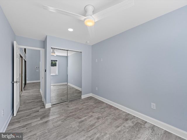 unfurnished bedroom featuring ceiling fan, a closet, and light hardwood / wood-style flooring