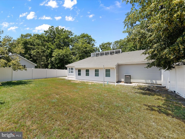 back of property with a lawn and central AC