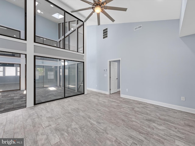 unfurnished living room with ceiling fan, high vaulted ceiling, and light hardwood / wood-style floors