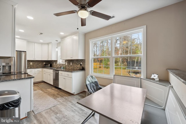 kitchen with appliances with stainless steel finishes, light hardwood / wood-style flooring, white cabinetry, and tasteful backsplash