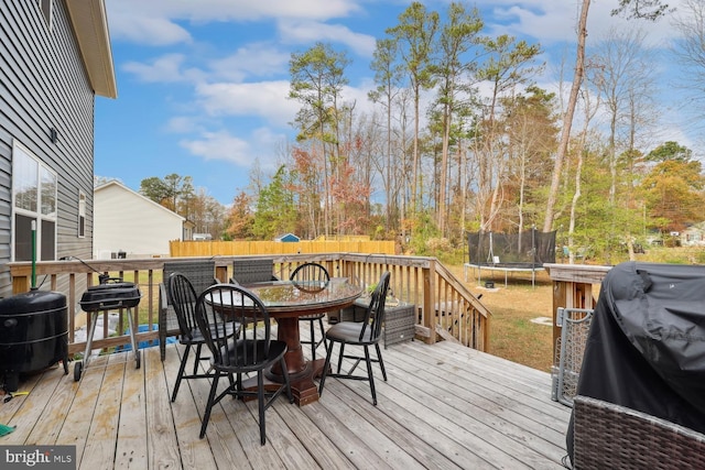 wooden terrace featuring a grill and a trampoline