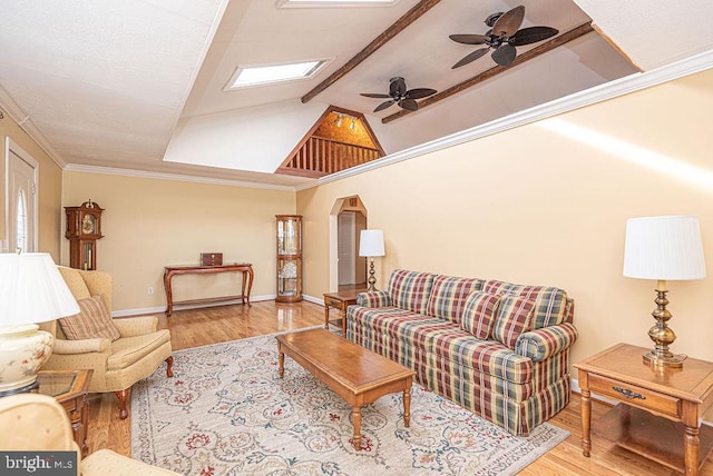 living room featuring light hardwood / wood-style floors, lofted ceiling with skylight, ceiling fan, and ornamental molding