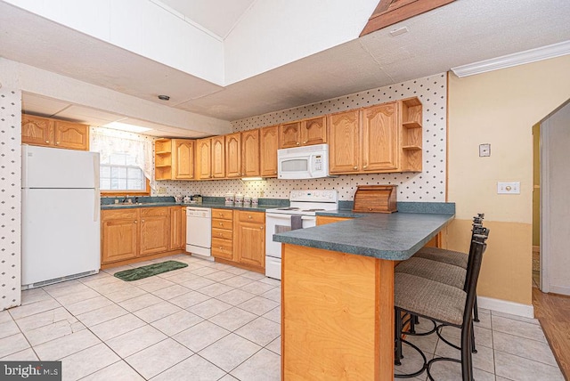 kitchen with light tile patterned floors, white appliances, kitchen peninsula, and a breakfast bar area