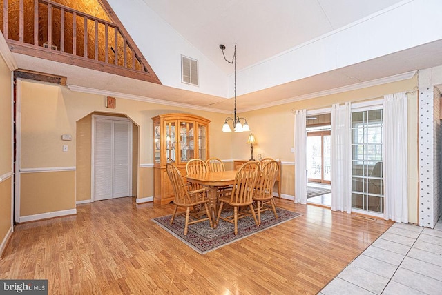 dining area with a towering ceiling, light hardwood / wood-style flooring, and ornamental molding