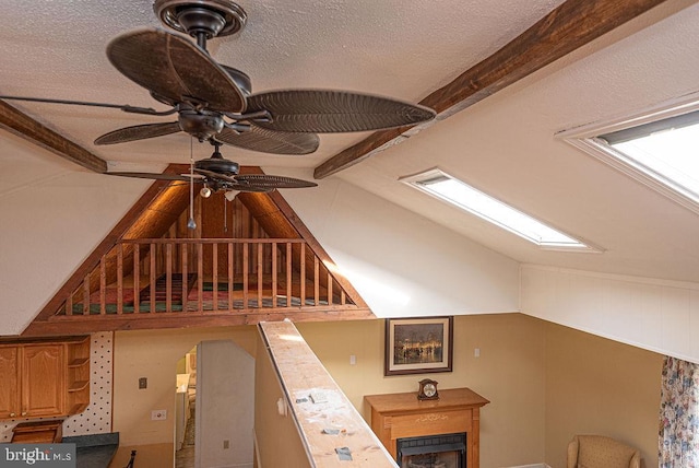 room details featuring a skylight, ceiling fan, beamed ceiling, and a textured ceiling