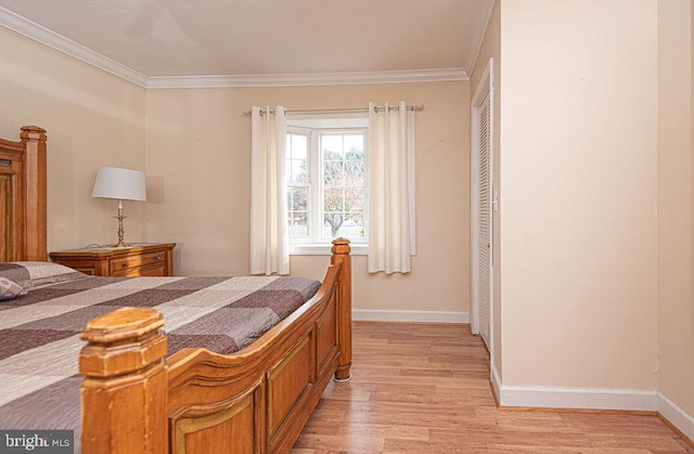 bedroom featuring ceiling fan, light hardwood / wood-style floors, ornamental molding, and a closet