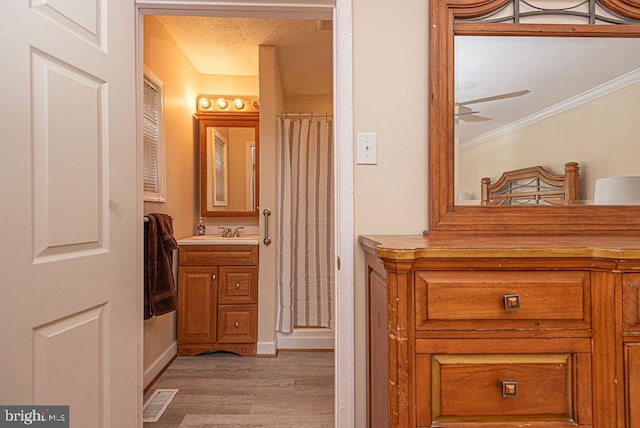 bathroom with ornamental molding, vanity, ceiling fan, hardwood / wood-style flooring, and curtained shower